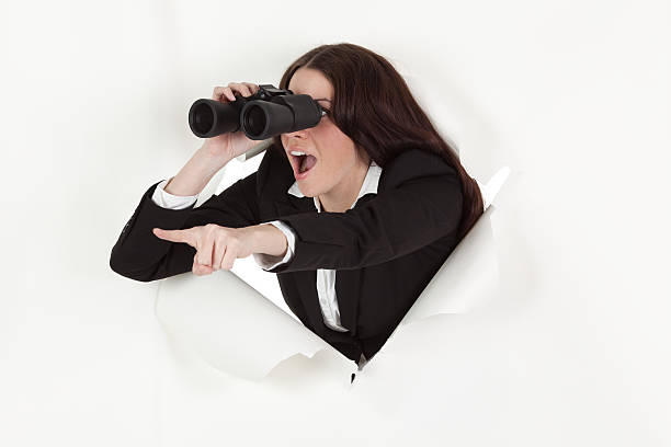 donna d'affari con il binocolo emergenti foro passante - human mouth paper screaming hole foto e immagini stock
