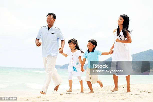 Famiglia Asiatica In Esecuzione Sulla Spiaggia - Fotografie stock e altre immagini di Accudire - Accudire, Adulto, Allegro