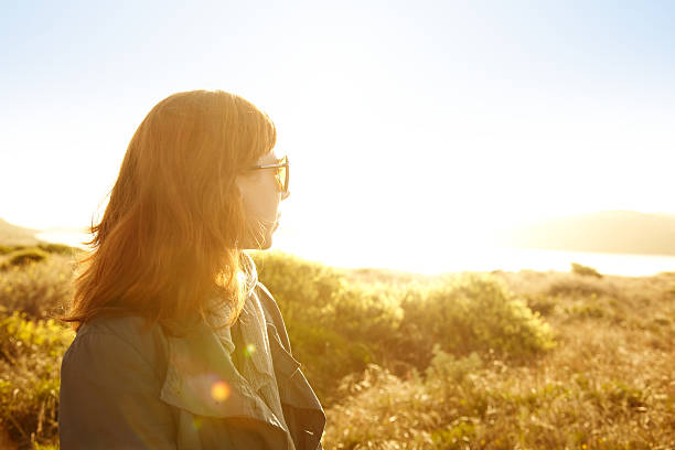 istock Woman in nature backlit by sun looking at ocean 183847108