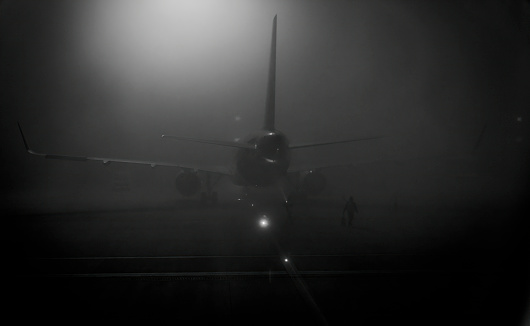 Photographer : Dr Raj K Rajnish \nI am not comfortable in writing a description. As Most my photos are spontaneous. Shot randomly during my visit.  Elements of surprise and constant search for theme is key. This shot I took while being on a Taxiway at Delhi IGI airport. I saw a lone guy walking to aircraft in extremely foggy day. It was dark cold calm. To match with the sense of feeling I shot in B&W.  Natural vinneating and just amount of light trickling through the fog in background of mighty aircraft ...ooops it was  joy. Hence the shot. I hope relate with the story.