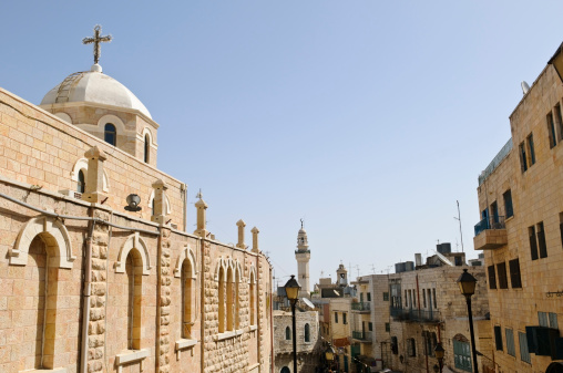 A Christian church stands along Paul VI Street, a pedestrian road that leads into Manger Square in the West Bank town of Bethlehem, Palestine. In the background is the minaret of the Mosque of Omar, which is located on Manger Square.