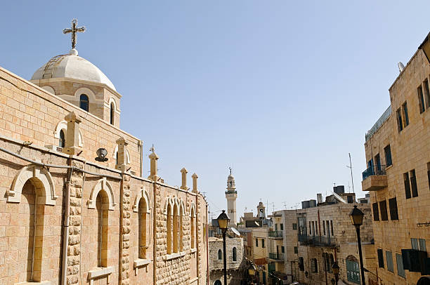 Church and Mosque in Bethlehem A Christian church stands along Paul VI Street, a pedestrian road that leads into Manger Square in the West Bank town of Bethlehem, Palestine. In the background is the minaret of the Mosque of Omar, which is located on Manger Square. bethlehem west bank stock pictures, royalty-free photos & images