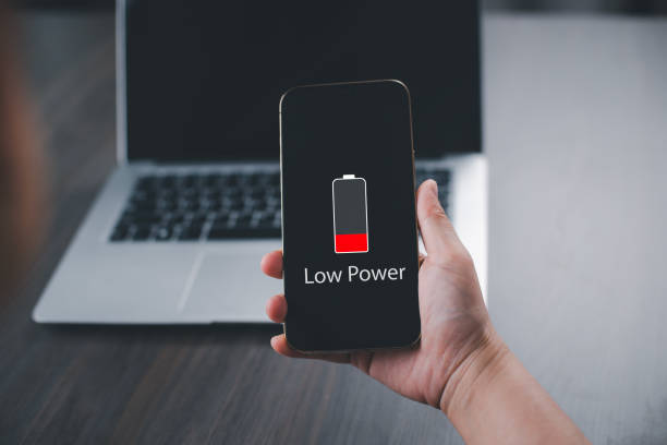 istock Close up man's hands using smart phone battery low charge battery screen, Businessman holding a smartphone  Low battery warning on a mobile phone. Need to connect the charger to the smartphone icon 1838511964