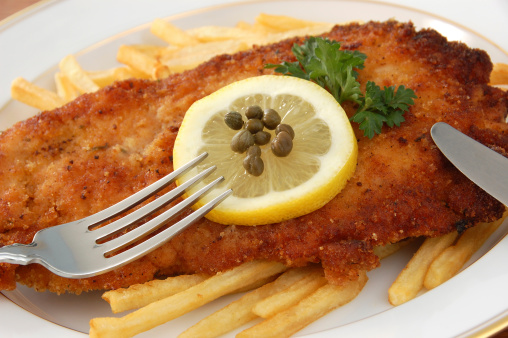 Classic Austrian breaded and fried veal cutlet (could also be pork or chicken) garnished with lemon and capers and served with french fries.More images from this series: