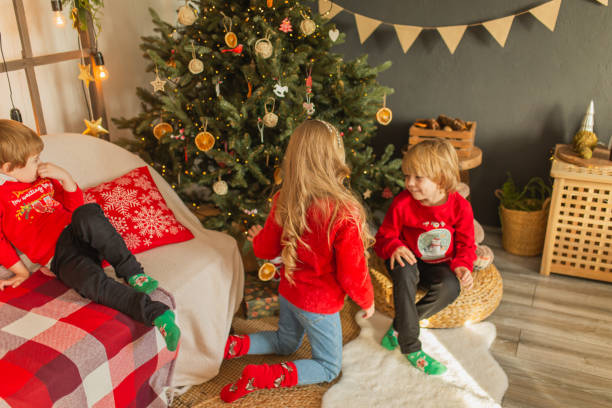 dzieci świętują boże narodzenie w czerwonym swetrze w domu. - child laughing blond hair three people zdjęcia i obrazy z banku zdjęć