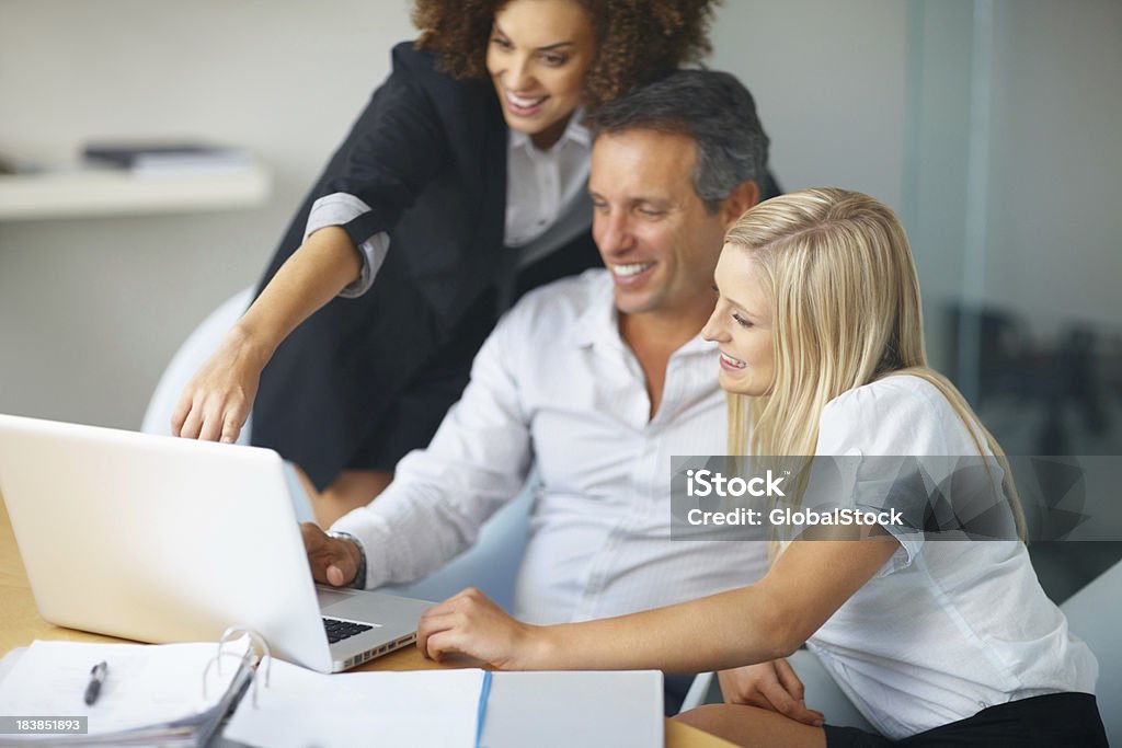 Colleghi guardando lo schermo del computer portatile durante una riunione - Foto stock royalty-free di Abbigliamento casual