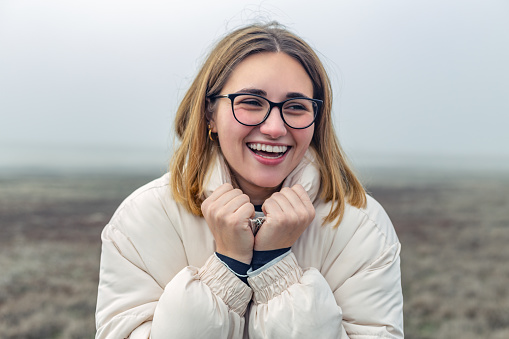 Laguna de Manjavacas, Mota del Cuervo, Castilla La Mancha, Spain. Young woman with glasses and winter clothing, smiling warmly in a rural setting with fog.
