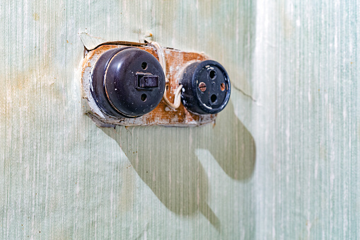 Bare light bulb illuminates a grunge ceiling with peeling paint and cracked plaster.