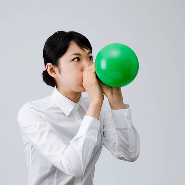 istock Young woman blowing up a balloon 183853402