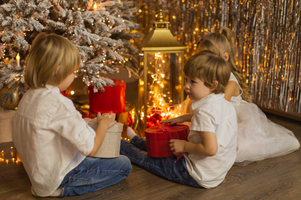 dzieci świętują boże narodzenie w domu. - child laughing blond hair three people zdjęcia i obrazy z banku zdjęć