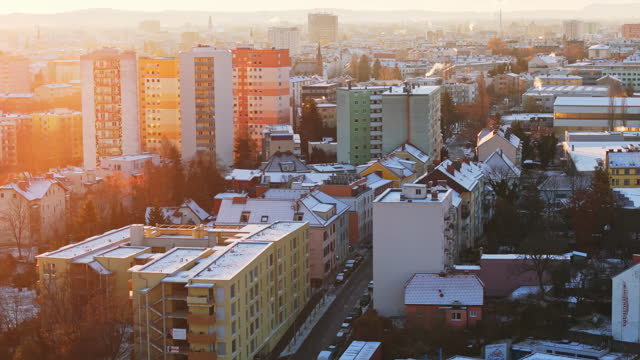 AERIAL Aerial Drone Shot of Snow-Covered City Buildings in Graz During Winter at Sunset