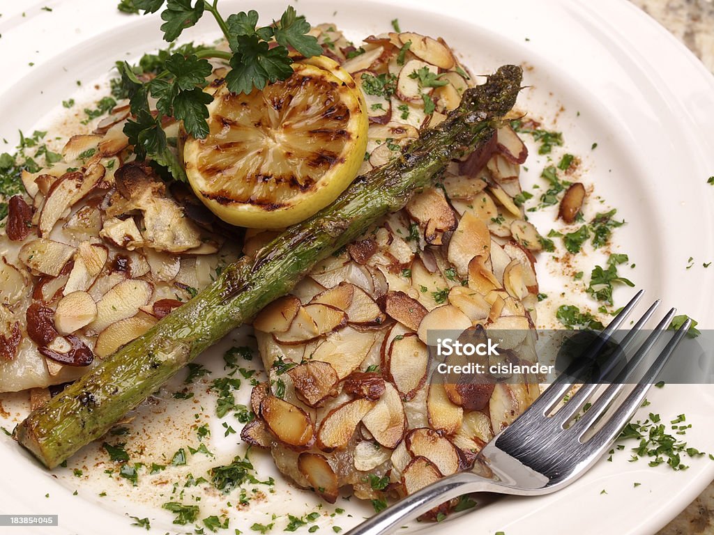 trout amandine "Fresh fillet of fish (trout, snapper, cod, sole, etc) crusted in almonds and drizzled with lemon butter. Garnished with grilled lemon and parsley. Roasted Asparagus spear." Fish Stock Photo