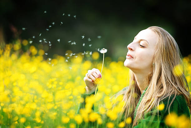 istock Young woman blowing a dandelion in meadow 183854149