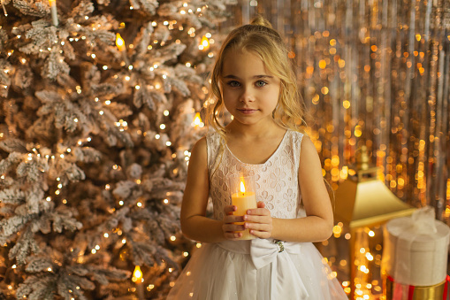 Blonde girl in white dress celebrating Christmas at home.
