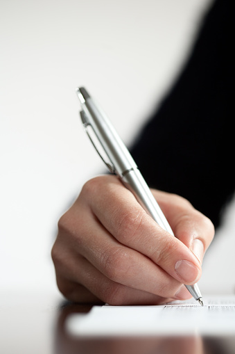 Closeup of a woman hand writing with a silver pen. Space for your text