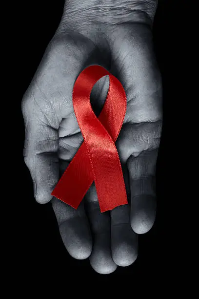 Close-up of had holding AIDS awareness ribbon