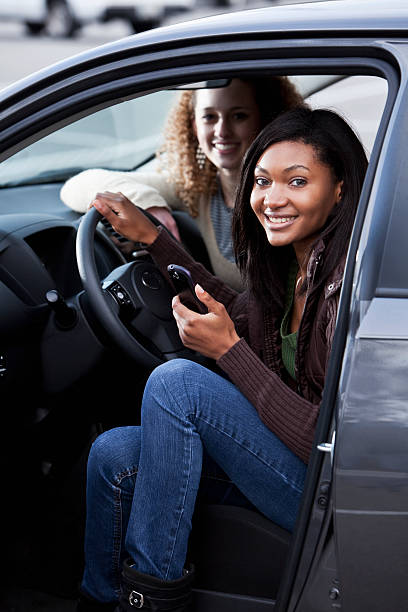 chica adolescente en que estacione coche de teléfono móvil - conductor asignado fotografías e imágenes de stock