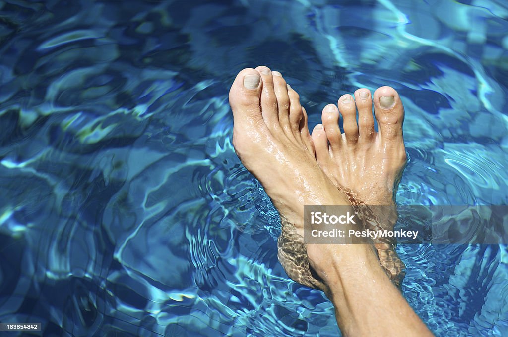 Пара мужской ног отдыха на волокнистой синей воде - Стоковые фото Бассейн роялти-фри