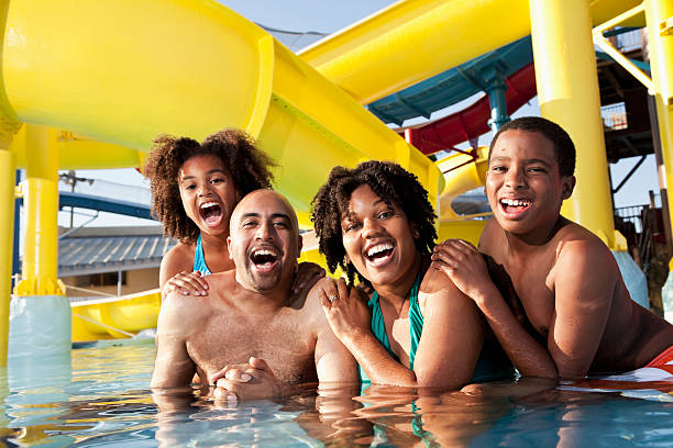familia afroamericana divirtiéndose en el parque acuático - swimming pool water people sitting fotografías e imágenes de stock