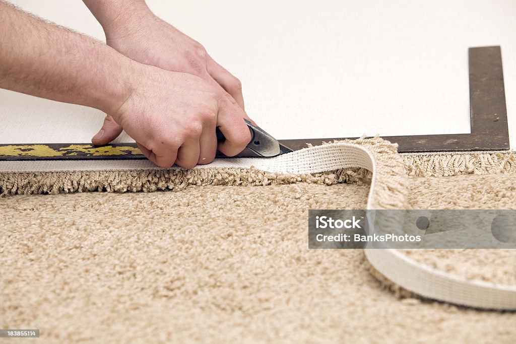 Carpet Installer Cutting with Knife and Straight Edge  Beige Stock Photo