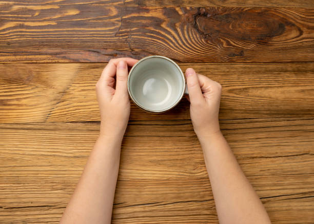 istock Hand Holds Cup, Empty Cup in Hands, Coffee Mug, Teacup Mockup, Cup in Arms on Wooden Table 1838553299