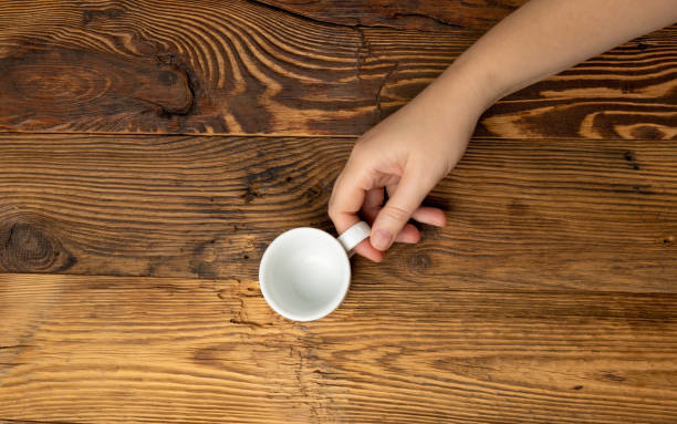 istock Hand Holds Cup, Empty White Cup in Hands, Coffee Mug, Teacup Mockup, Cup in Arms on Wooden Table 1838553314