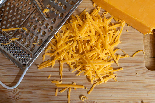 Cheddar Cheese Flat Lay on cutting board with cheese grater