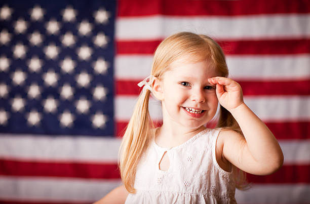幸せな少女敬礼、アメリカの国旗 - child military saluting flag ストックフォトと画像