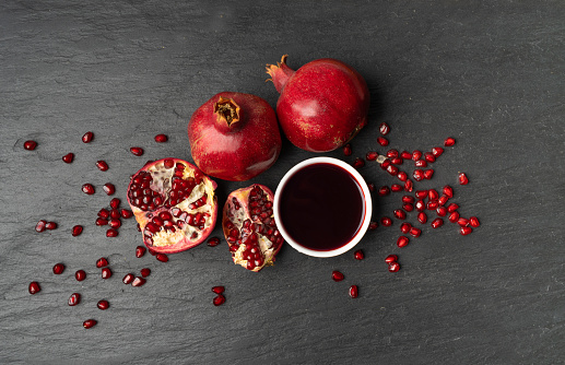 Pomegranate Sauce, Sirup, Dressing, Red Ripe Fruit Syrup with Red Ripe Whole Fruit Group, Organic Pomegranates Sauce on Natural Black Stone Background
