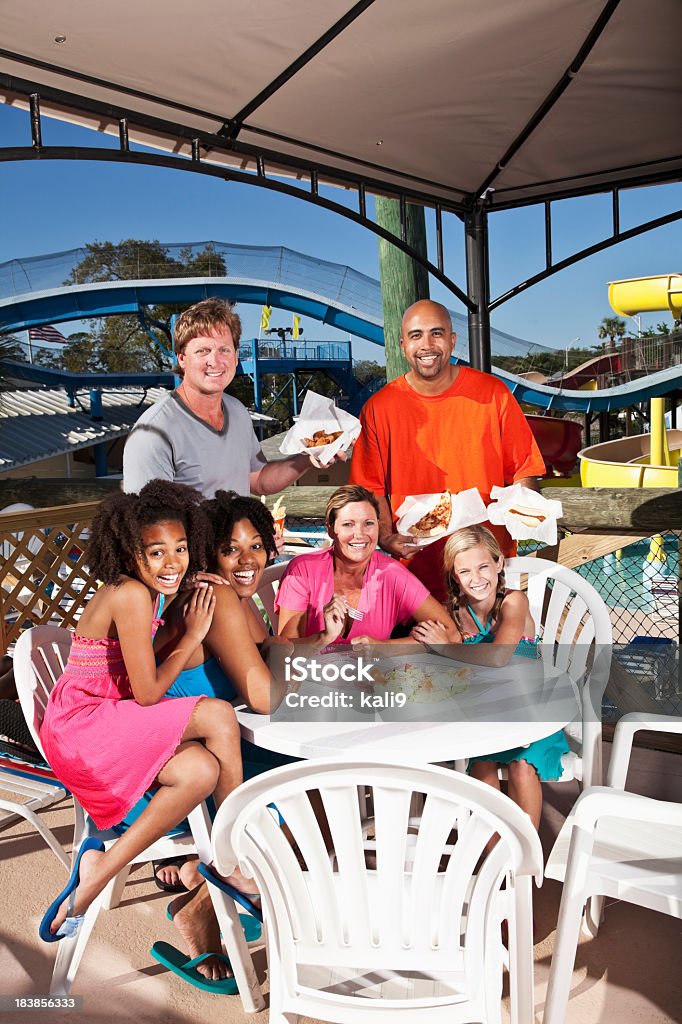 Families having lunch at water park Two families enjoying pizza and salad at water park.  (Water slide in background) Amusement Park Stock Photo