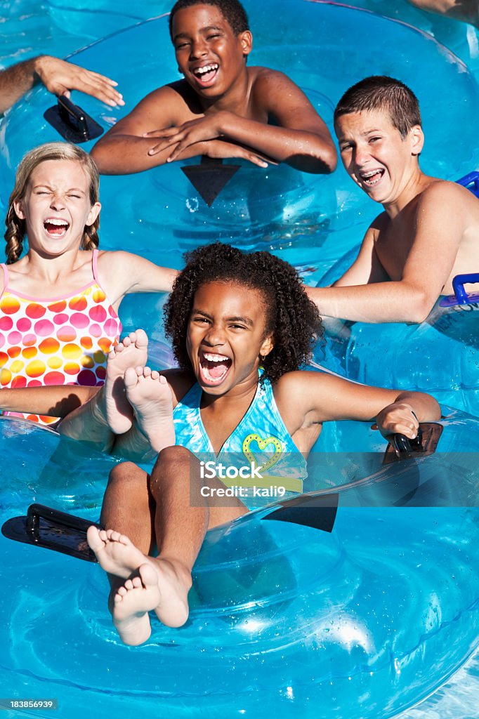 Enfants multiraciales flotter sur innertubes au parc aquatique - Photo de Enfant libre de droits