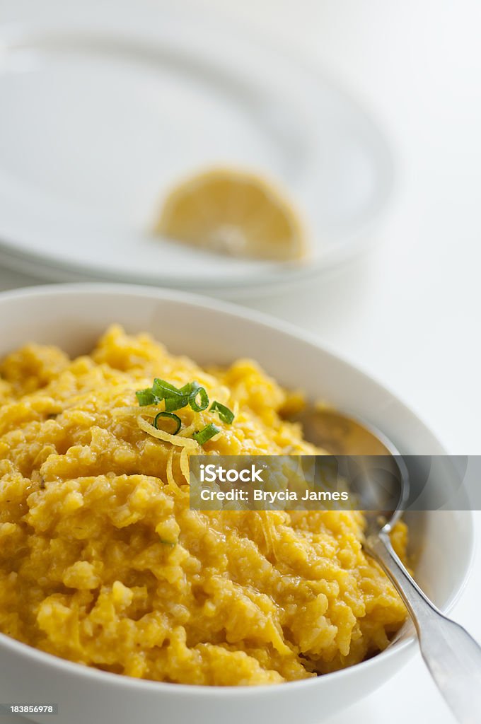 Carrot-Lemon Risotto Bowl of Carrot-Lemon Risotto shot on an angle with serving plates in the background.Similar Images: Risotto Stock Photo