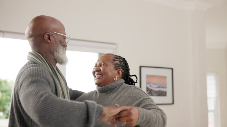 Elderly African couple, dancing and happy in home, holding hands and laugh for moving together with comic and music. Senior man, black woman dancer and smile with steps, playful and bonding with love