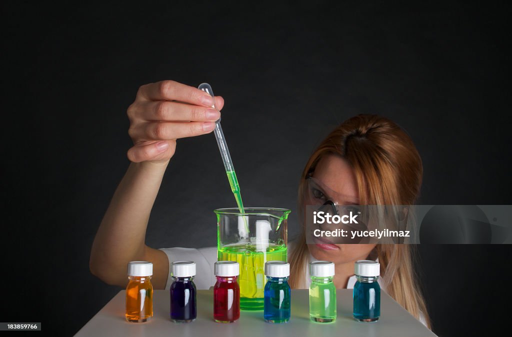 Scienziato donna lavorando con prodotti chimici liquidi colorati - Foto stock royalty-free di Adulto