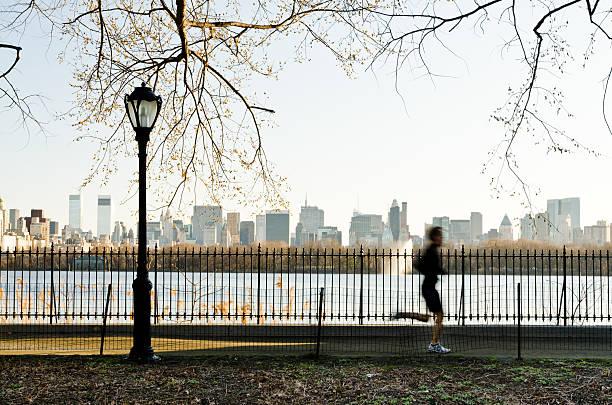Runner silhouette in Central park against pond and Midtown skyline