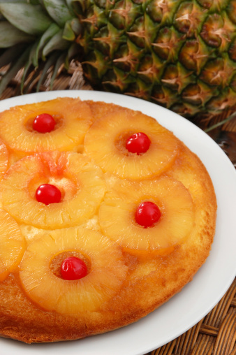 A retro classic dessert, pineapple upside down cake garnished with maraschino cherries.