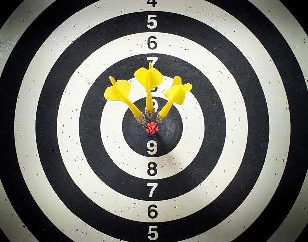 Target type dart board with three yellow darts in the red bullseye.
