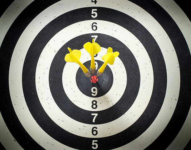 Three yellow darts in the black and white dartboard bullseye stock photo