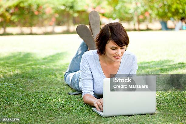 Bonita Jovem Mulher Usando Laptop Deitado Na Relva - Fotografias de stock e mais imagens de 16-17 Anos