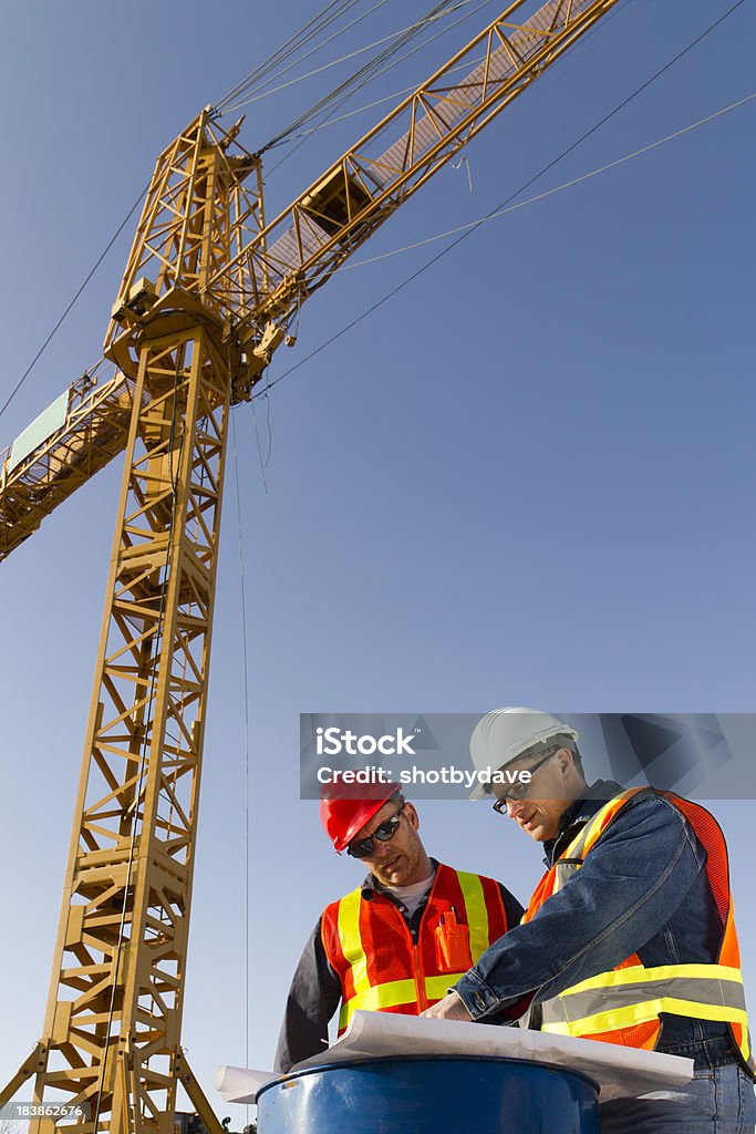 Crane Meeting A royalty free image of two engineers underneath a construction crane. Construction Site Stock Photo