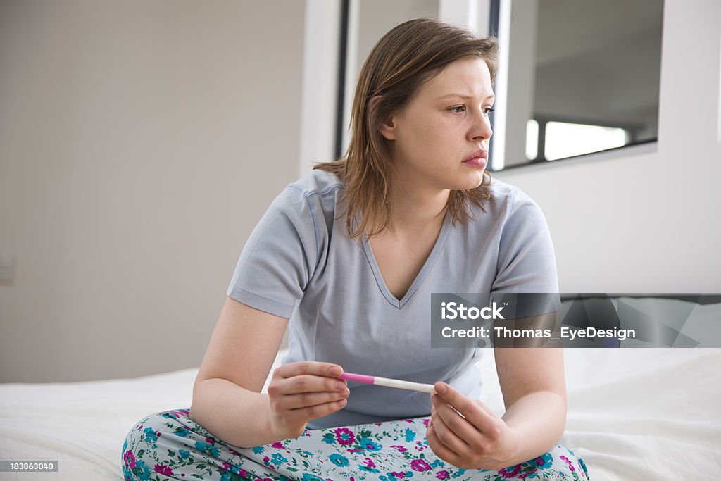 Junge Frau Pensively Sitzbereich mit einem Schwangerschaftstest - Lizenzfrei Anfang Stock-Foto