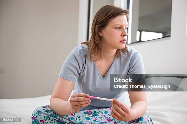 Junge Frau Pensively Sitzbereich Mit Einem Schwangerschaftstest Stockfoto und mehr Bilder von Anfang