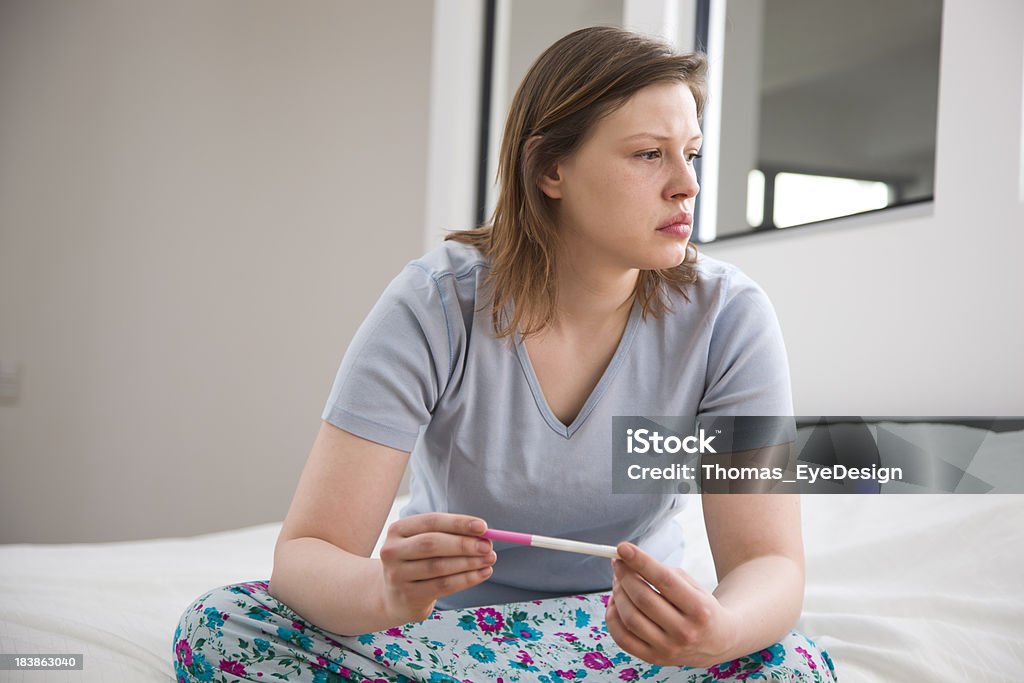 Pensively Giovane donna seduta con un Test di gravidanza - Foto stock royalty-free di Adulto