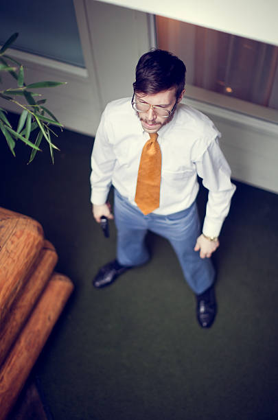 A spy or undercover agent with sideburns, mustache, and vintage 1970's / 80's style clothes standing in an outdoor hotel or motel corridor hallway, gun in hand.  View looking down from above balcony.  Vertical, with copy space.