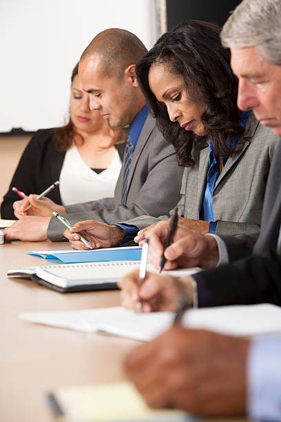 Business people writing on meeting table stock photo