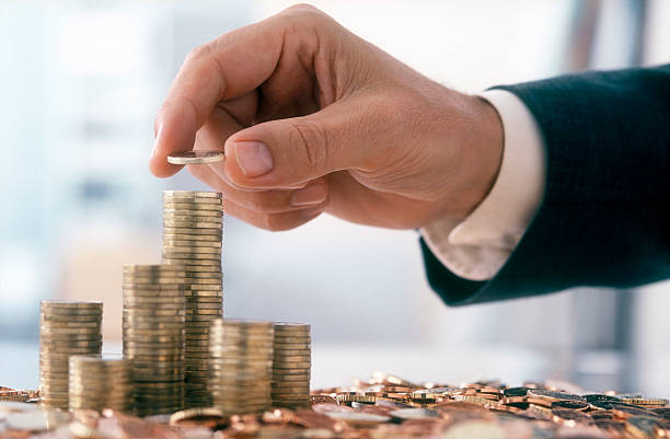 Businessman is stacking coins Hand of a mid adult man, wearing a siut, is stacking Euro coins. (2XL-File) wealth stock pictures, royalty-free photos & images