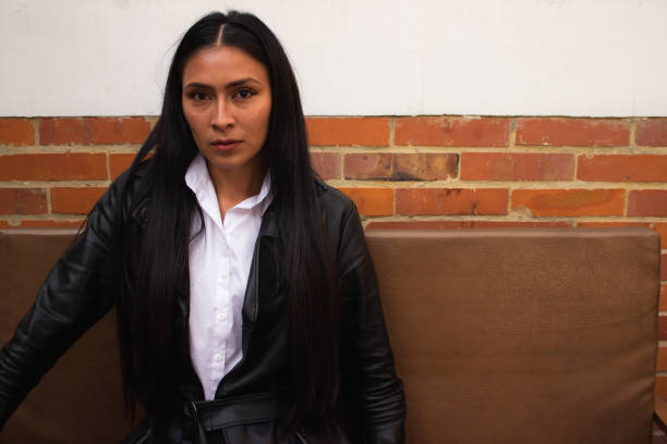 istock young woman posing and sitting on a couch with a brick wall 1838652653