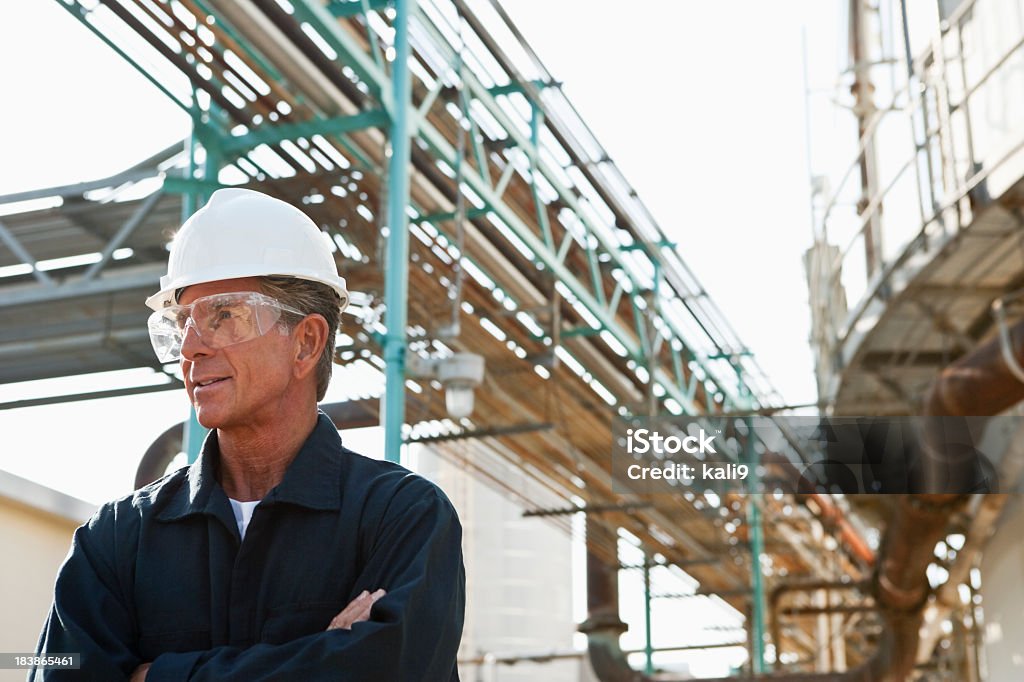 Uomo anziano al lavoro come ingegnere presso un impianto industriale - Foto stock royalty-free di Raffineria