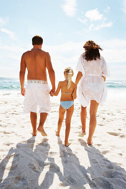 istock Daughter walking with parents on the beach 183866219