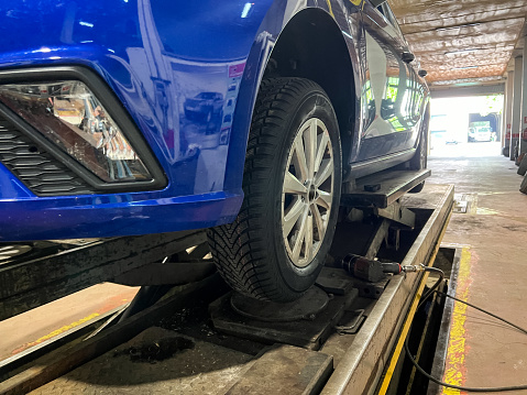 Close up of a wheel of a car uploaded on a lift in a car workshop for changing and repairing wheels